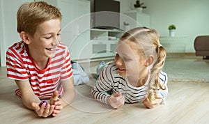 Portrait of two cheerful children laying on the floor and playing with colorful dices