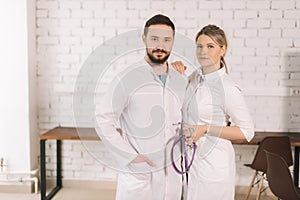 Portrait of two confident successful professional doctors wearing hospital uniform posing together