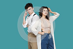 Portrait of two confused thoughtful brunette stylish partner standing, looking away, scratching head and thinking that to do and