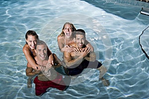 Portrait of two couples in swimming pool at night