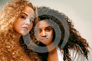 Portrait of two curly girls. Afro and blond