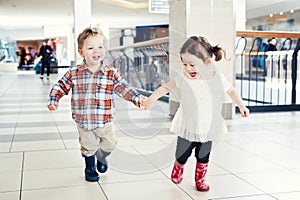 Portrait of two cute adorable babies children kids toddlers friends siblings running in mall store