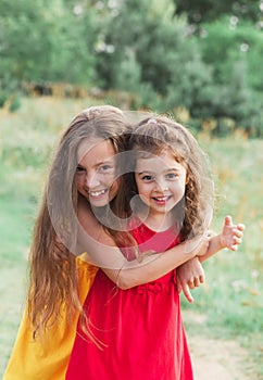 Portrait of Two Cute little girls embracing and laughing at the countryside. Happy kids outdoors