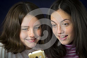 Portrait of two cute sisters looking at cell phone