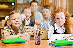 Portrait of two diligent girls looking at camera at workplace wi