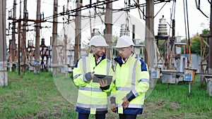 Portrait of two diverse modern factory workers wearing hardhats and uniform use digital tablet computer discussing