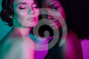 Portrait of two dreamy nude women enjoying life bonding isolated over vivid violet green gradient neon color background