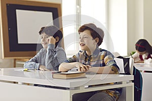 Portrait of two elementary school boys sitting in class and listening to the teacher.