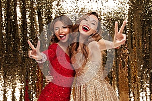Portrait of two excited cheery women in sparkly dresses photo