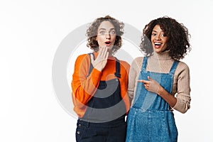 Portrait of two excited women hugging and pointing finger