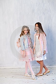 Portrait of two fashionable schoolgirl girls girlfriend in pink clothes