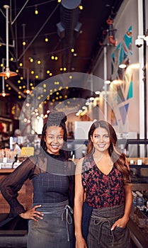 Portrait Of Two Female Coffee Shop Owners Standing At Sales Desk photo