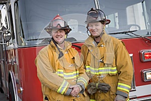 Portrait of two firefighters by a fire engine