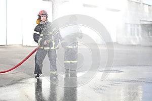 Portrait of two fireman holds and adjust nozzle photo