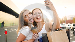 Portrait of two funny girls making face and having fun while making selfie photo of mobile phone at shopping mall