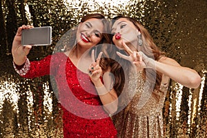 Portrait of two funny happy women in sparkly dresses