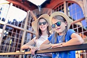 Portrait of two girls in hats and sunglasses on the background of an old building