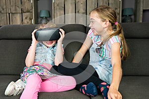 Portrait of two girls, they are having fun with a virtual reality headset at home