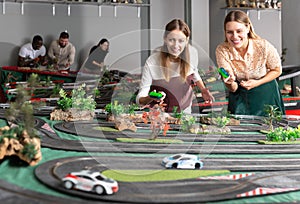 Portrait of two girls playing with slot car racing track