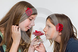 Portrait of two girls smelling red rose