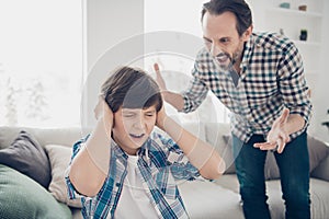 Portrait of two guys evil frustrated fury dad and depressed pre-teen son in casual checked shirt sitting on couch