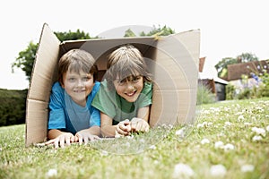 Portrait Of Two Happy Boys Lying In Cardboard Box