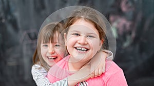 Little girls hugging in front of chalkboard