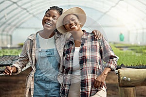 Portrait of two happy farmers. Young farmers hugging one another. Cheerful colleagues standing in their greenhouse. Two