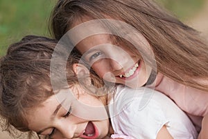 Portrait of Two Happy little girls laughing and hugging at the summer park. Happy childhood concept