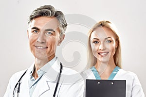 Portrait of two happy male and female doctors in medical uniform looking at camera and smiling. Strong medical team