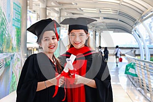 Portrait of two happy smiling graduated students holding  certificate, young beautiful Asian women looking at camera so proud on