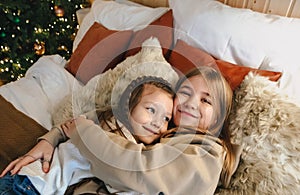 Portrait of two happy smiling little girls sisters hugging while spending time together on Christmas