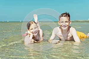 Portrait of two happy teen children liying in water of baltic sea beach at summer holidays