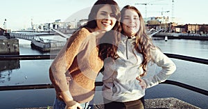 Portrait of two happy teenager friends hugging and looking to camera with smile in front of Drogheda River. Shot on RED