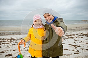 Portrait of two happy teenagers staing on coast of Baltic sea at windy rainy weather