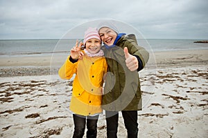 Portrait of two happy teenagers staing on coast of Baltic sea at windy rainy weather