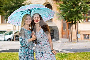 Portrait of two happy women with umbrella in street