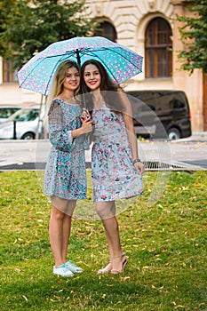 Portrait of two happy women with umbrella in street