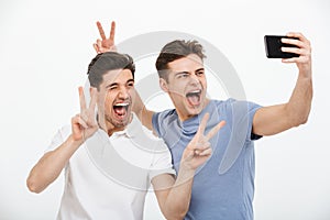 Portrait of two happy young men showing peace gesture