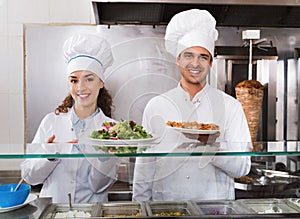 Portrait of two hospitable chefs with kebab at fastfood place