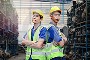 Portrait of two industrial engineer workers man wearing helmet with arms crossed, standing at manufacturing plant factory with