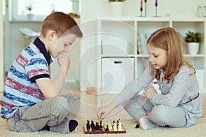 Portrait of two little children concentrated playing chess