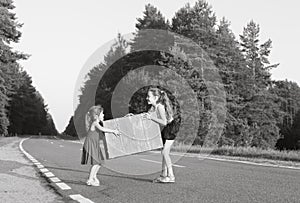 Portrait of two little girls carring at vintage suitcase on the road at sunset. Sisters enjoyed a Holidays over summer nature