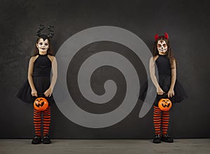 Portrait of two little girls in Halloween images standing on both sides on black background.