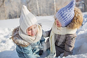 Portrait of two little girls play in a snow in winter