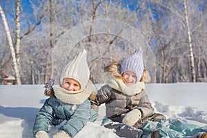 Portrait of two little girls sit and smile in a winter day