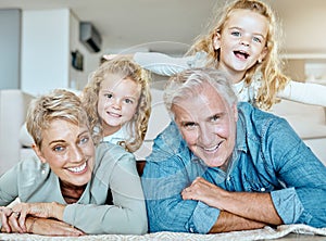 Portrait of two little girls spending time with their grandparents on the lounge floor at home . Mature caucasian couple