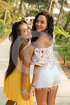 Portrait of two lovely young Asian women in who turned around and smiled at camera in tropical luxury hotel. Tourism.