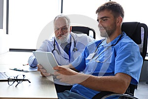 Portrait of two male doctors using digital tablet in a bright medical office