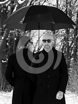 Portrait of two men under an umbrella in the park